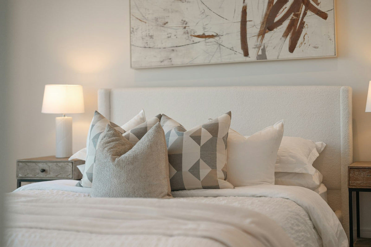 Neutral bedroom with layered pillows and warm lamps